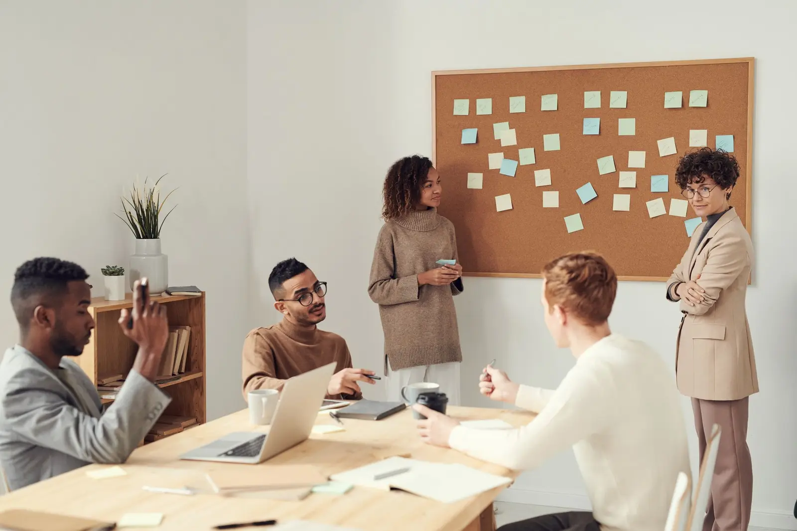 A team meeting in a bright room in front of a wall of sticky notes