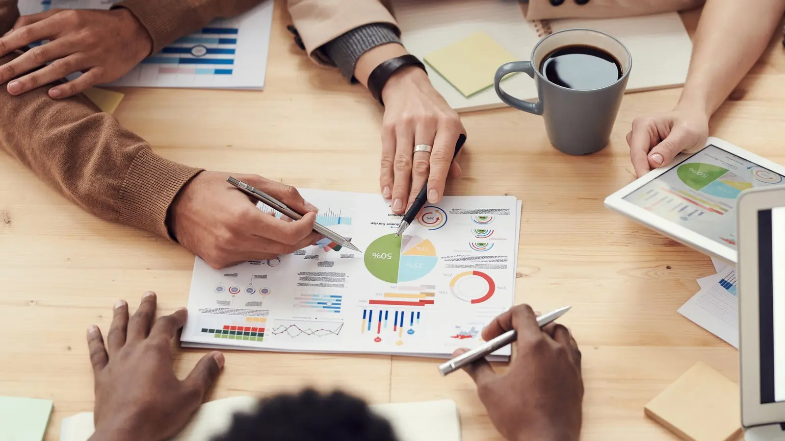 Colleagues pointing at printed charts and notes on a shared table